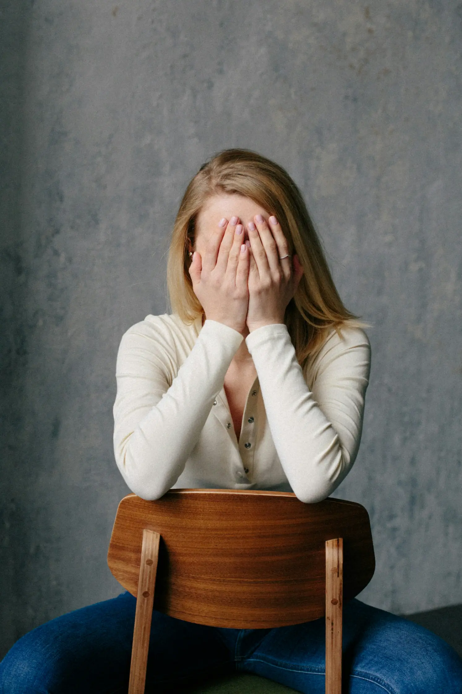 Femme assise, visage dans les mains : surcharge émotionnelle et fatigue mentale